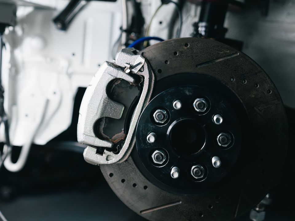 A brake disc and caliper on a car in a workshop